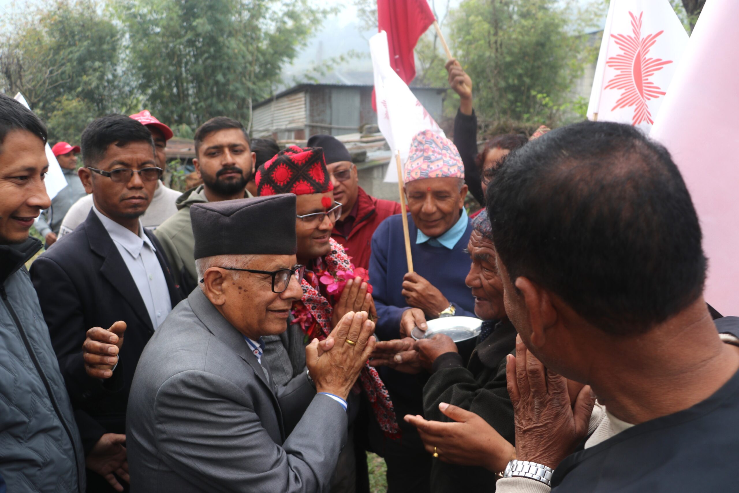अठहत्तर बर्षीय नेता सोमनाथ अधिकारी प्यासी उम्मेदवार रश्मी आचार्यको लागि मत माग्दै घरदैलोमा